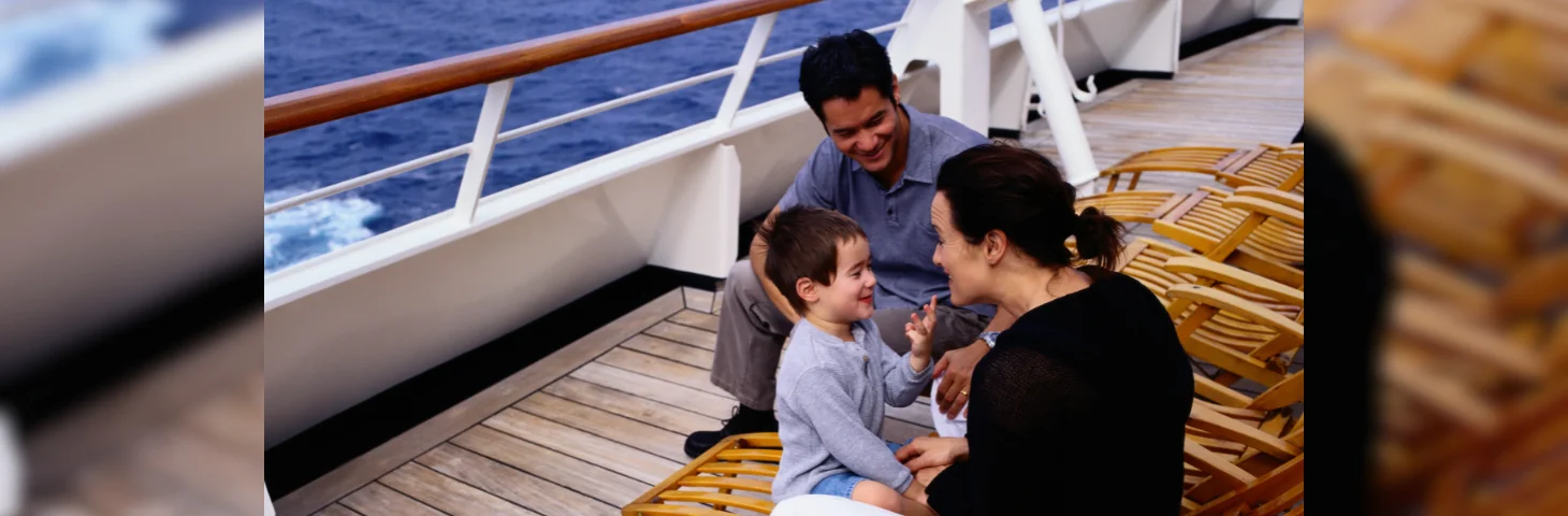 A family of three, two parents and a child, on the deck of a cruise ship.