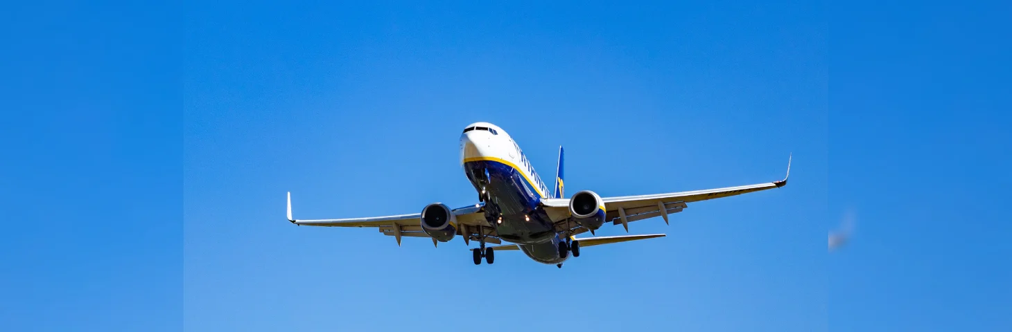 A Ryanair flight taking off against a clear blue sky.