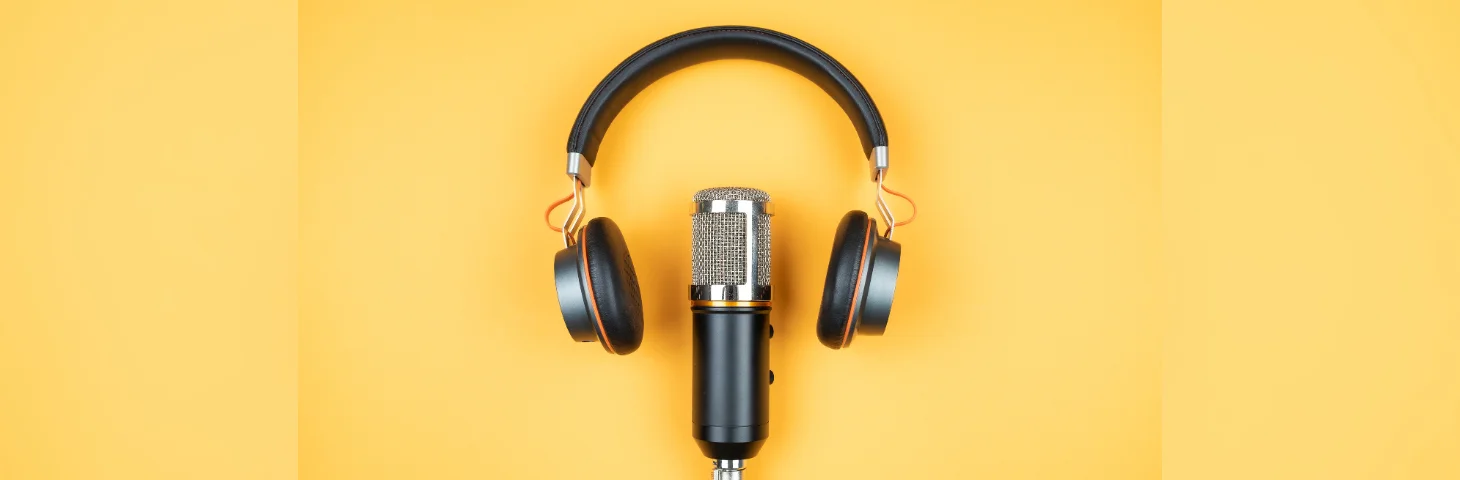 A podcast microphone and headphones over a warm yellow background