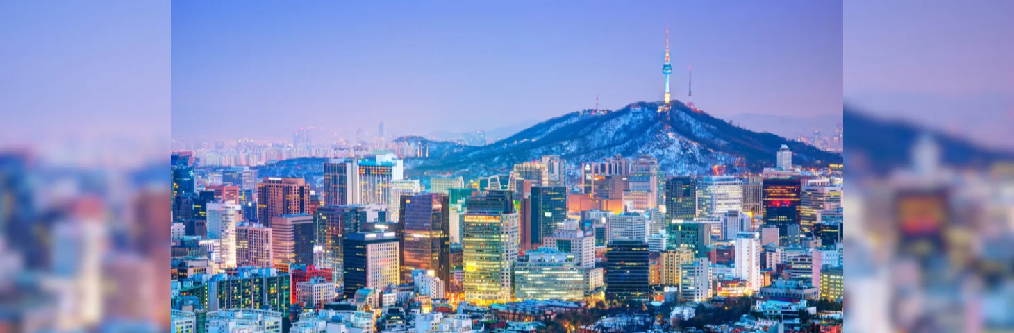 The Seoul skyline at sunset against a blue/purple sky.